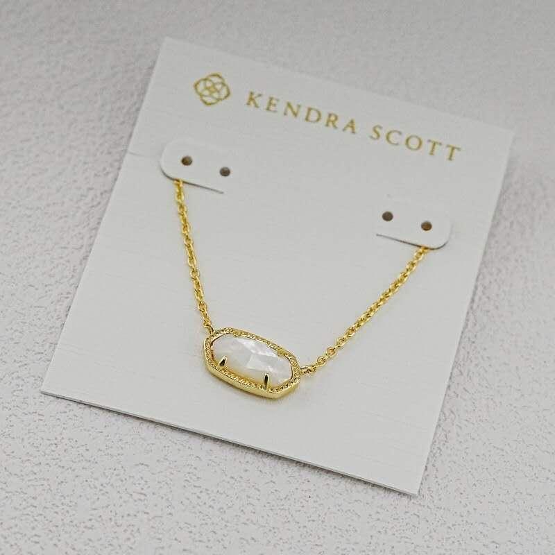 Gold pendant necklace with oval stone centerpiece on a display card