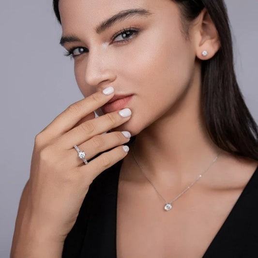 Round moissanite solitaire ring with pavé band on finger, silver tone