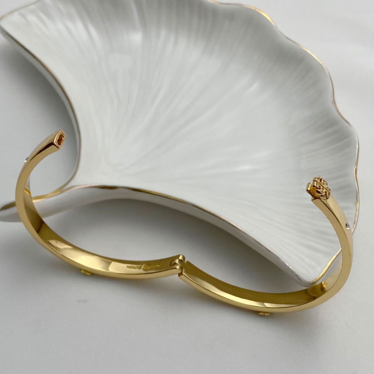 Gold hinged bangle side view with opening hinge and pavé detail charm