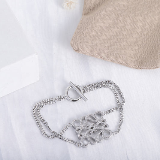 Silver openwork charm bracelet shown from the side, hinged clasp at center