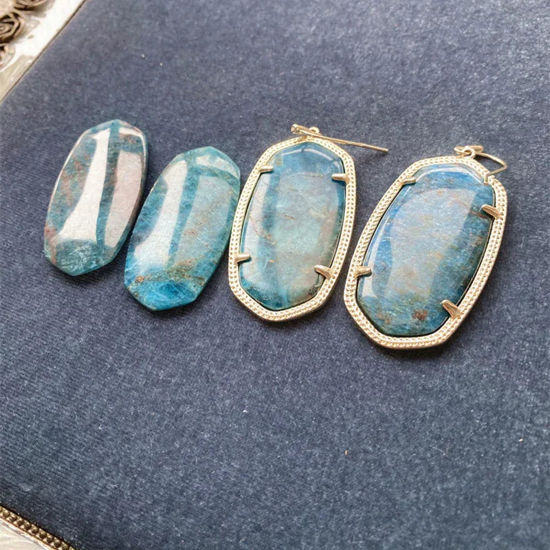 Gold-tone drop earrings with blue oval stone, outlined border, hook back