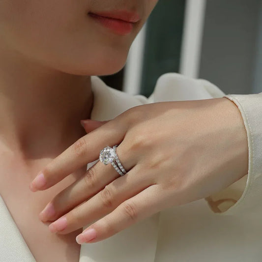 Silver moissanite ring on hand, showing round center stone and pavé side band.