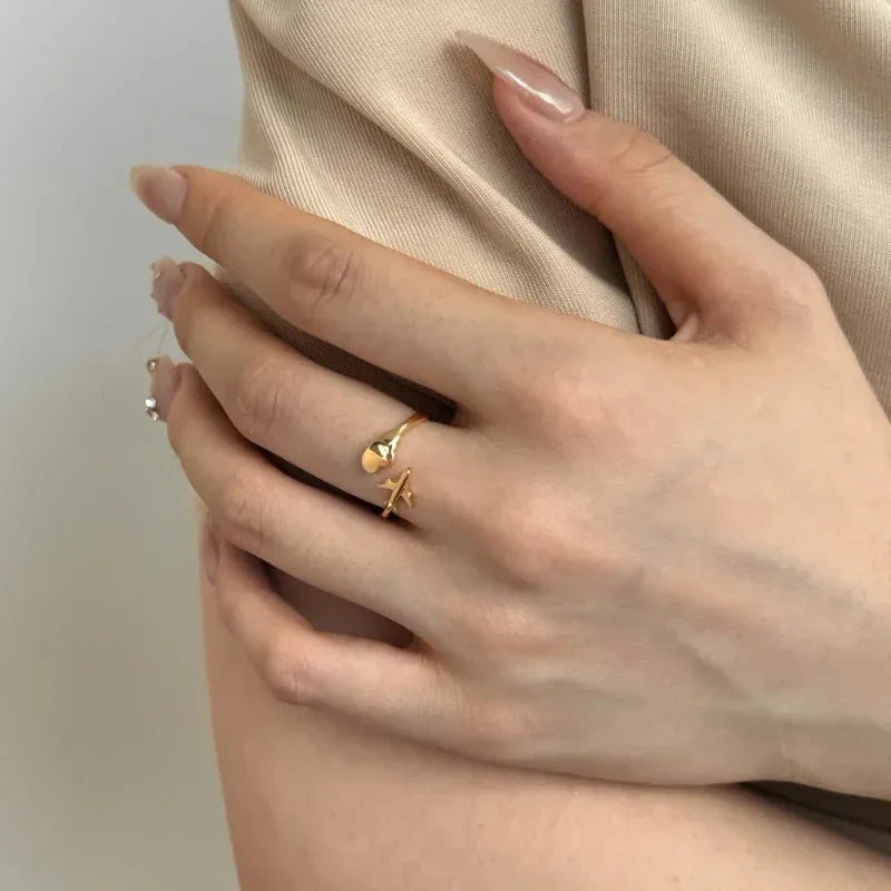 Adjustable airplane and cloud open ring, gold-tone, on finger near sleeve