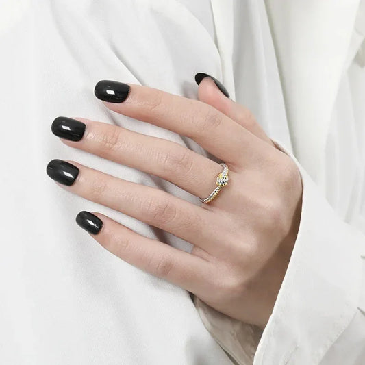Twisted knot ring in silver and gold, worn on finger with black nail polish