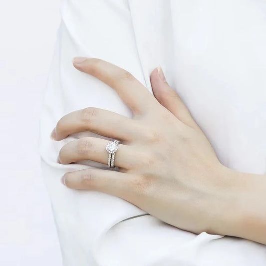 Silver ring set on hand, with round center diamond and pavé band