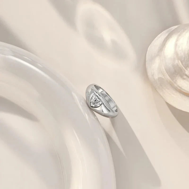 White gold heart-shaped CZ ring with bezel-set heart stone on a chunky polished band, side view
