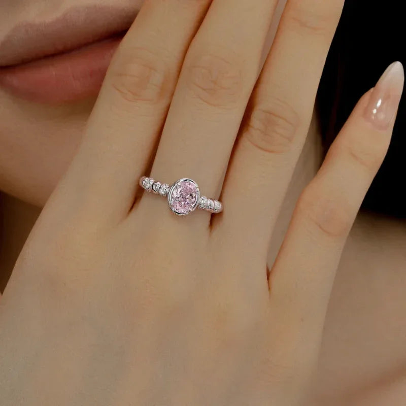 Sterling silver oval CZ eternity wedding ring with pink oval center stone and pavé band on finger
