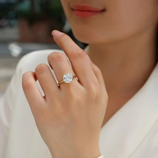 Gold moissanite engagement ring on finger with round center stone