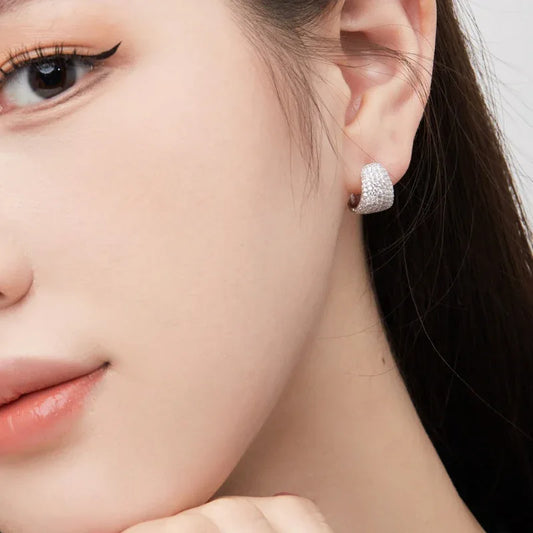 Sterling silver teardrop stud earrings with pavé sparkle, shown on ear