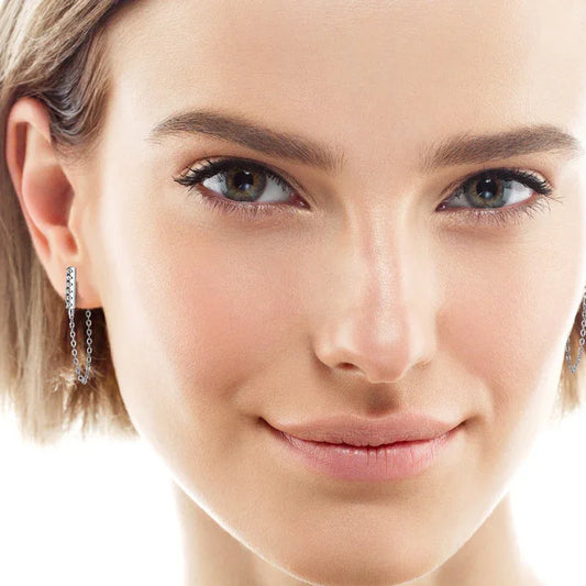 Dangling chain stud earrings shown on model’s ear, with a row of small sparkle stones