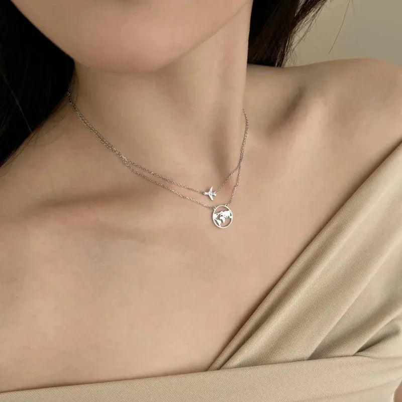 Silver-tone pendant necklace with airplane charm and round world-map globe pendant