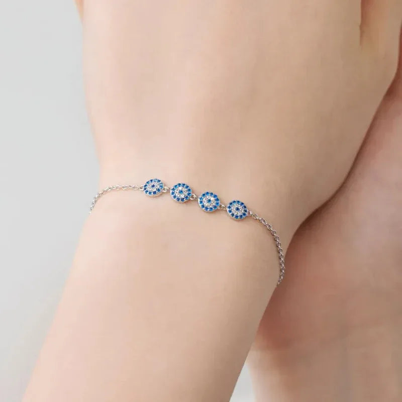 Close-up of bracelet: four blue evil-eye charms on silver-tone chain