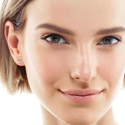 Moissanite stud earrings on ear, round bezel-set stone with spiral ring halo
