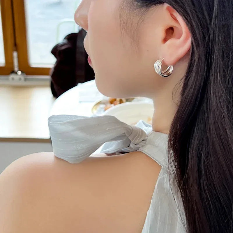 White gold interlaced fold hoop stud earrings, side profile close-up