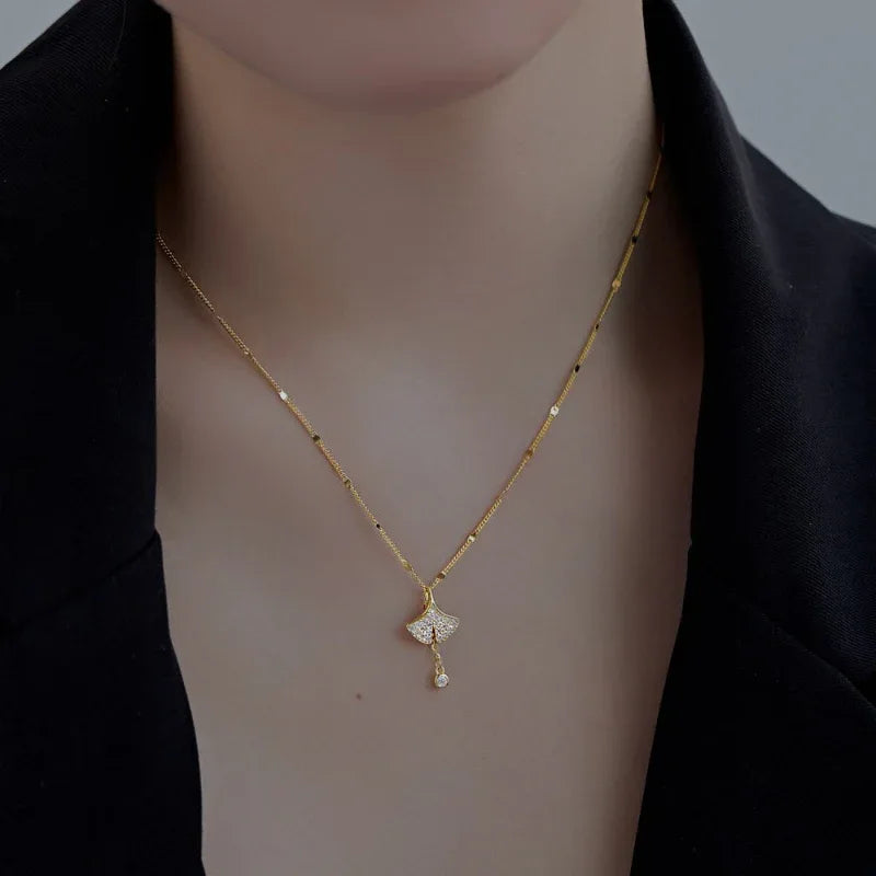 Gold-tone ginkgo leaf pendant necklace with dangling round crystal charm