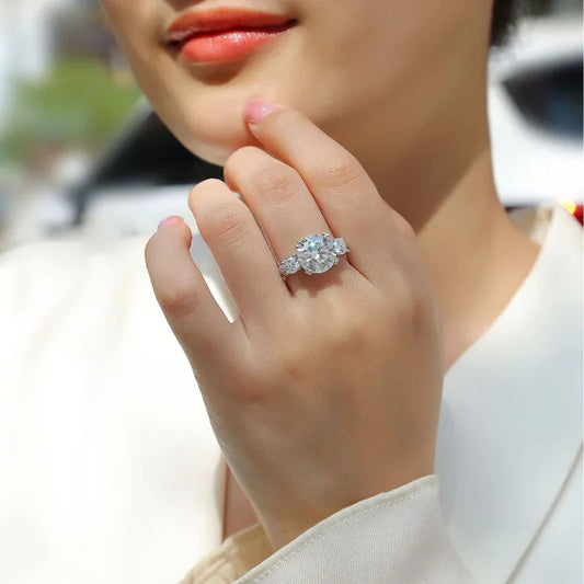 White gold moissanite cluster engagement ring on finger with round center stone