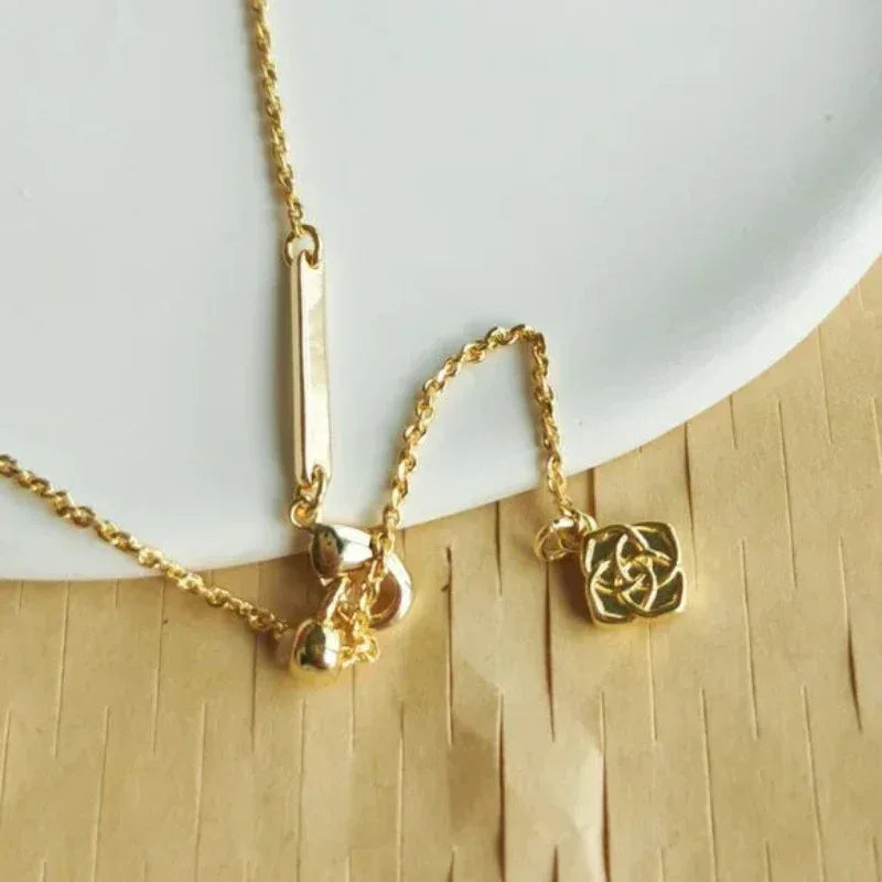 Gold-tone necklace with triangular white-pearl pendant and round charm