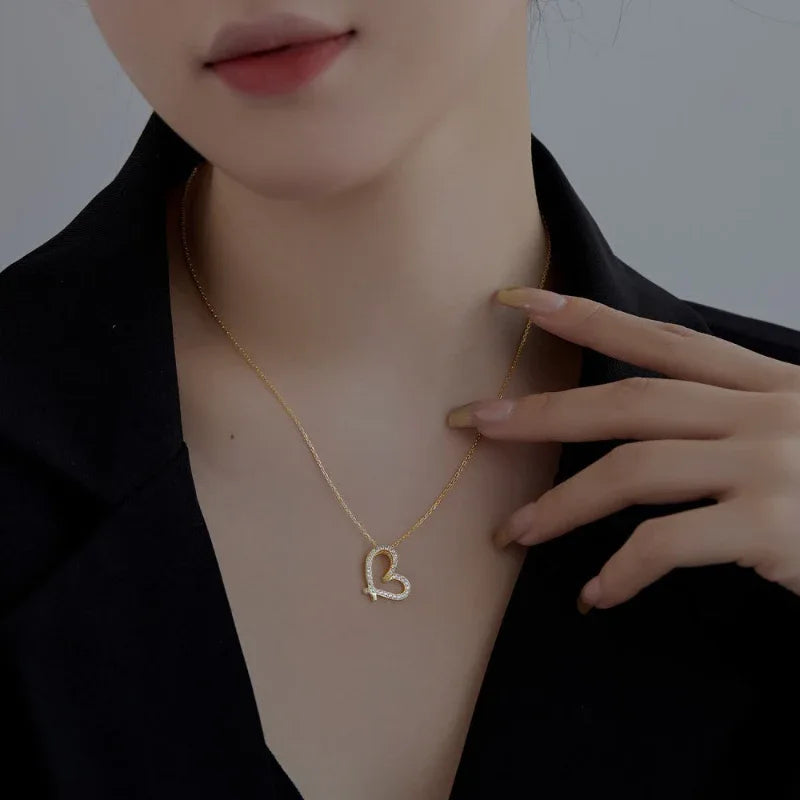 Gold-tone hollow heart love pendant necklace with rhinestone sparkle worn on model