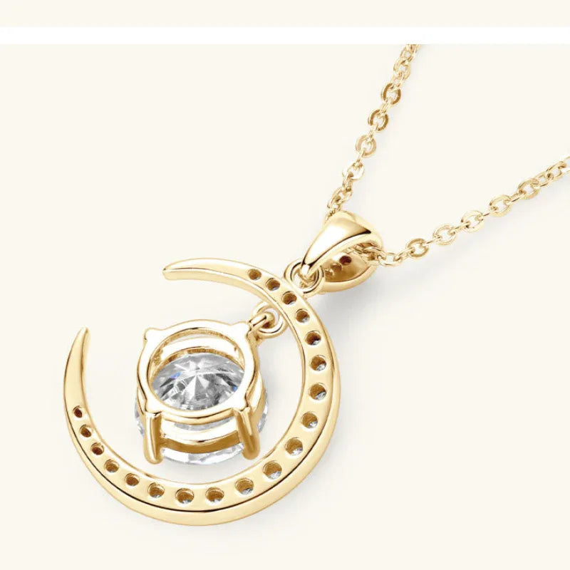 Gold crescent moon pendant with round moissanite in prongs, close-up on chain.
