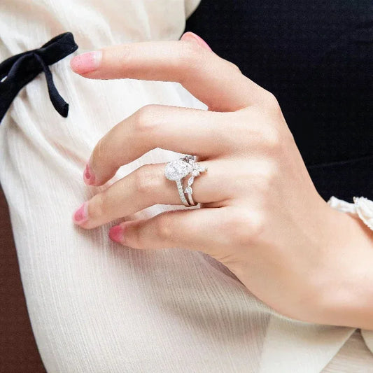 White gold ring with oval center stone and pavé halo, worn on finger