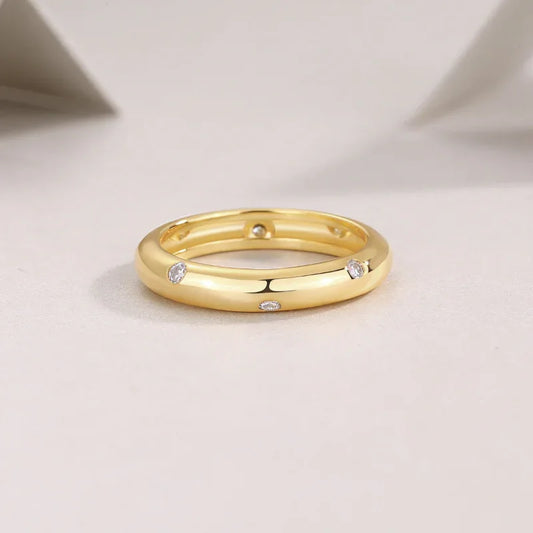 Gold-tone wedding ring, top view, with small round stones set along the band
