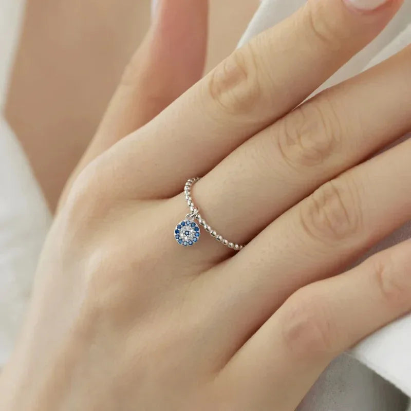Silver-tone evil eye ring with blue bezel and halo of crystals on finger