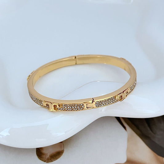 Gold-tone pave diamond openable bangle with row of sparkling stones and hinge clasp