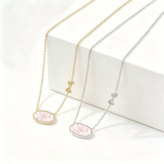 Gold-tone bow charm oval pendant necklace with pink floral enamel