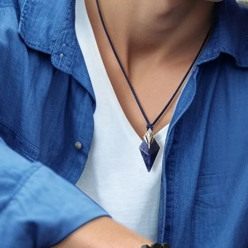 Lapis-style trident pendant on dark cord necklace, triangular blue stone at chest