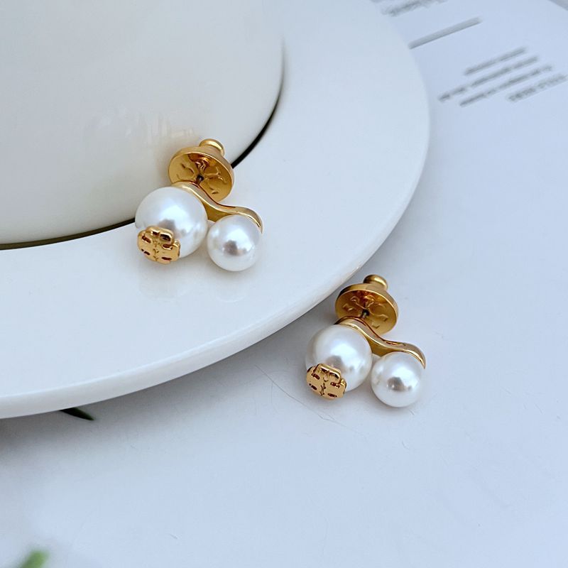 Gold-tone logo pearl pendant earrings with white pearl clusters and emblem caps, side view