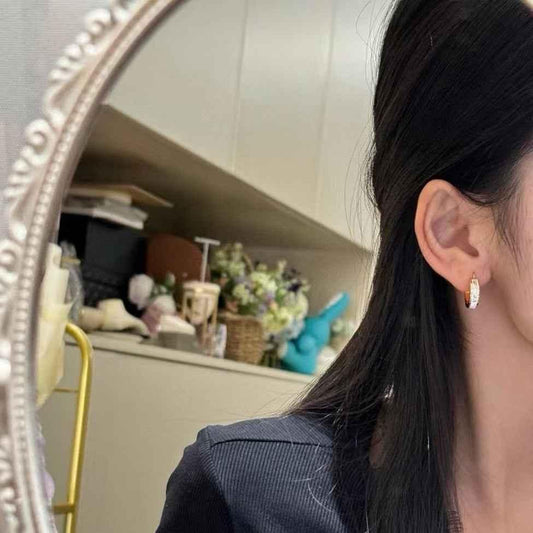 Gold hoop earrings with MIU MIU logo band, worn on ear