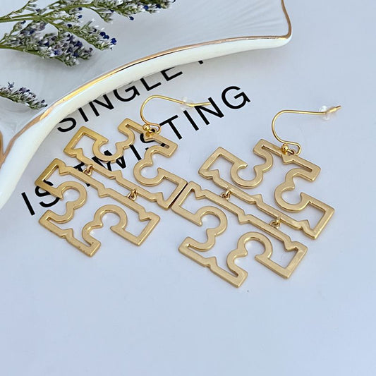 Gold geometric drop earrings with dangling openwork logo panels and fishhook hooks.