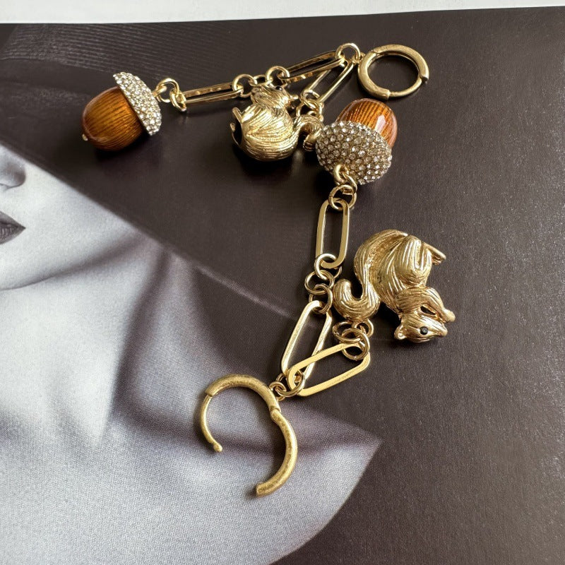 Gold-tone squirrel dangle earrings with orange acorn beads and curved wire links
