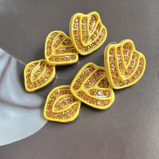 Gold-plated leaf pendant earrings with yellow enamel hearts and sparkling crystal detailing