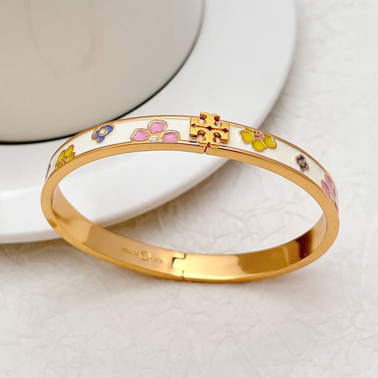Gold-tone enamel flower and paw motif bangle with hinged clasp