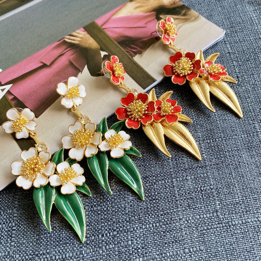 Gold-plated enamel floral drop earrings with white flowers, green leaves, and tapered drops