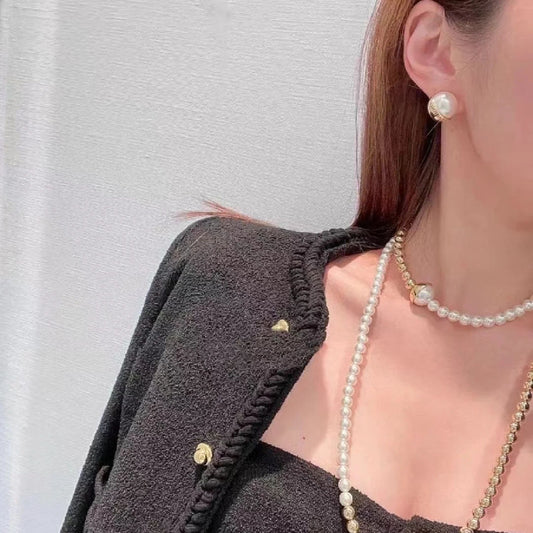 Gold-tone half-circle stud earrings with white half-pearl, worn