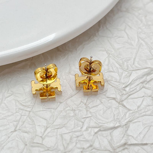 Gold-tone logo stud earrings with white shell inlay, showing round stud backs and posts