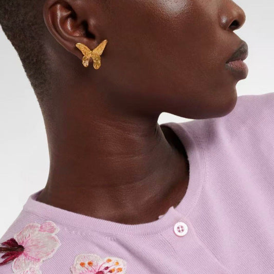 Gold butterfly earrings on model ear, small stud with textured wings