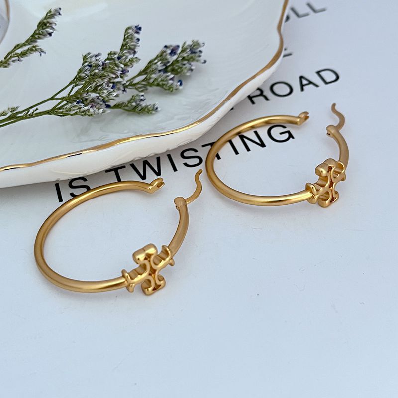 Gold-tone Tory Burch logo hoop earrings with butterfly-like charm detail