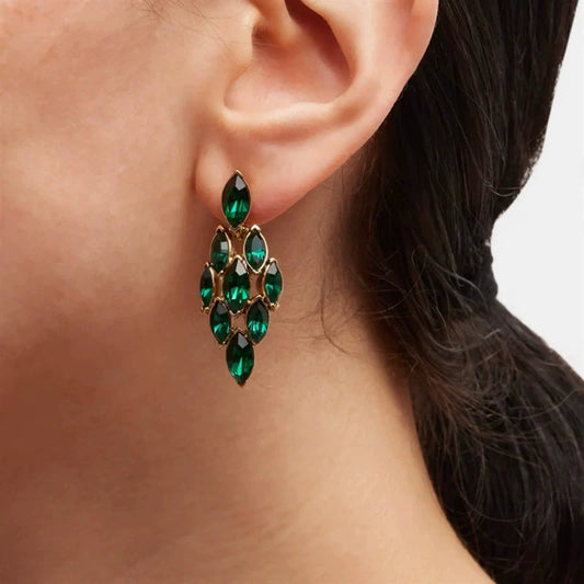 Green diamond-shaped rhinestone earrings with gold-tone settings, worn on the ear