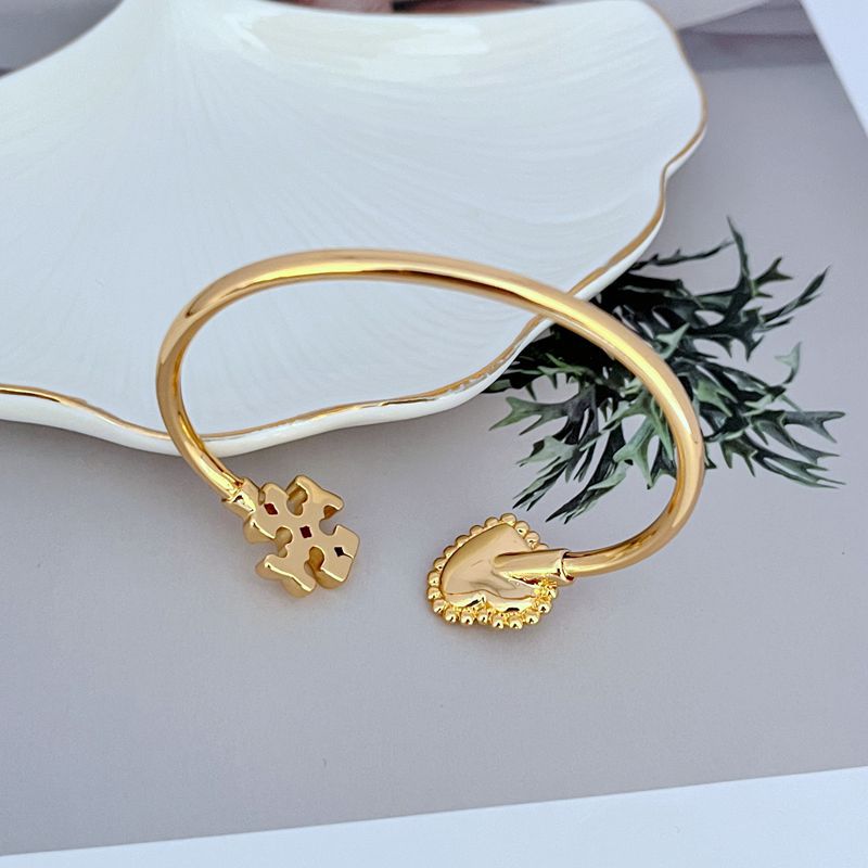 Gold-tone open bangle with heart toggle clasp and mother-of-pearl heart detailing