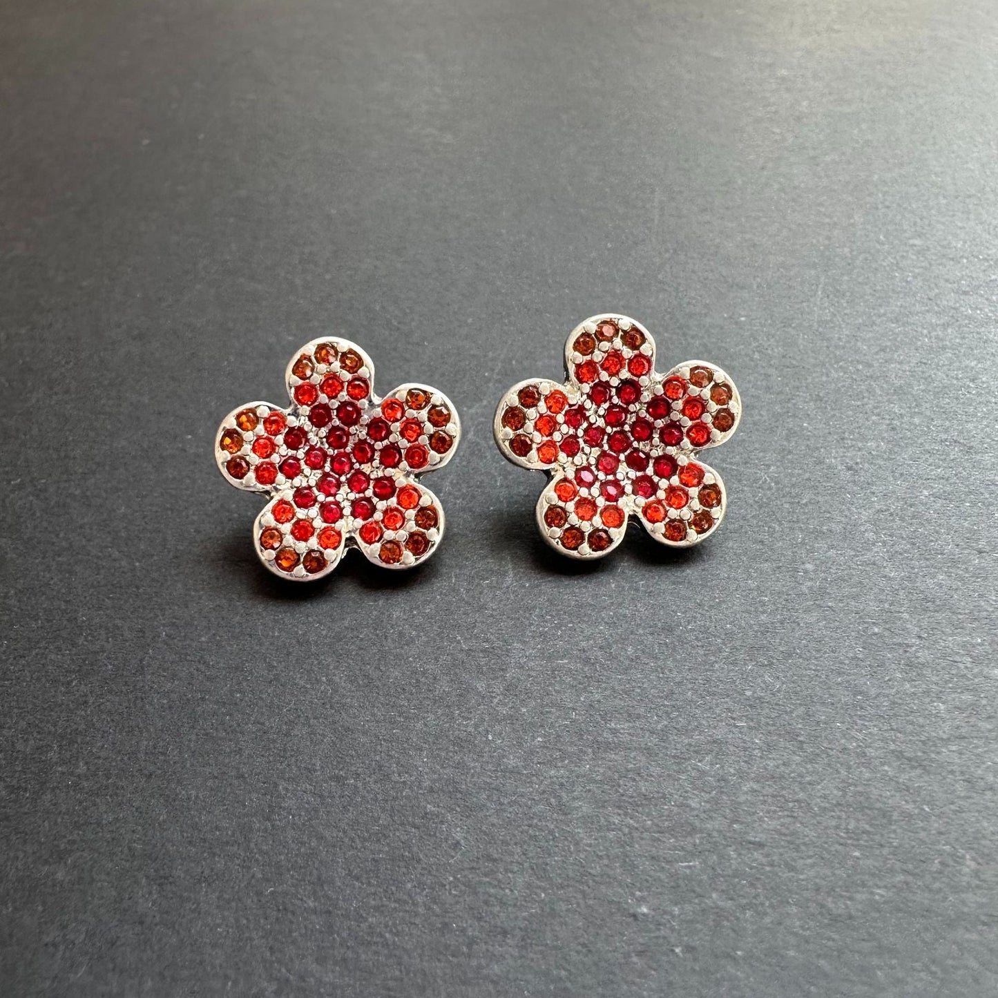 Silver-tone floral stud earrings with red rhinestones