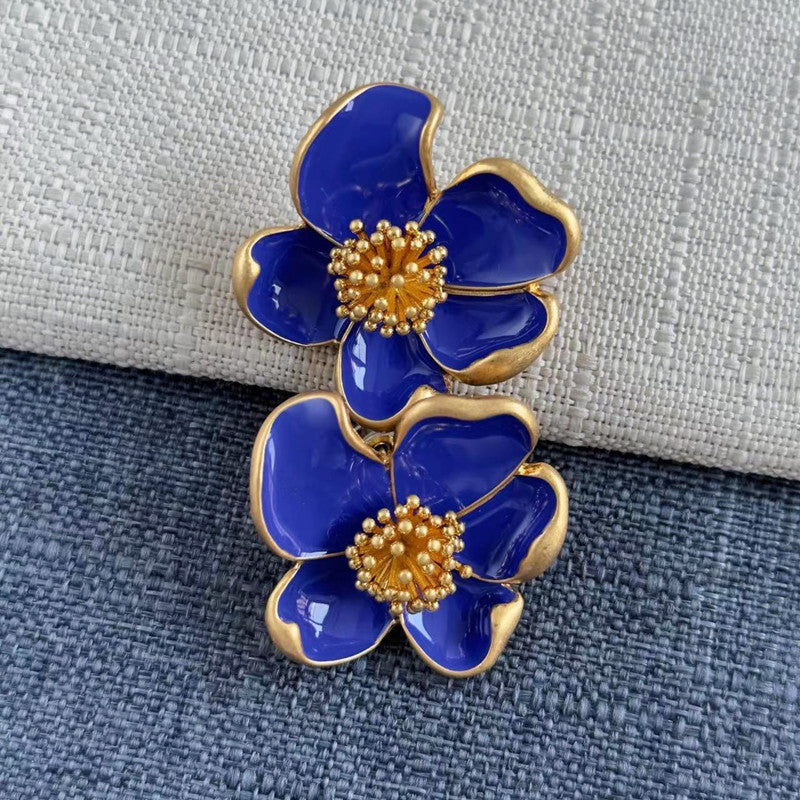 Deep blue enamel floral stud earrings with gold-tone petals and gold beaded centers.
