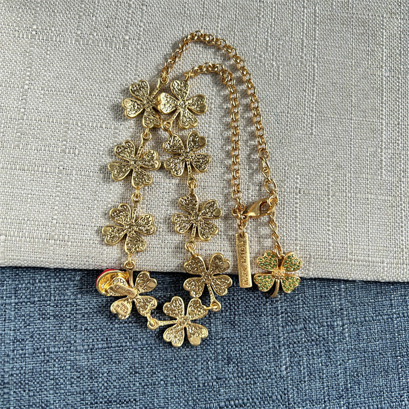 Gold-tone clover crystal necklace with ladybug bead charm, hanging chain view