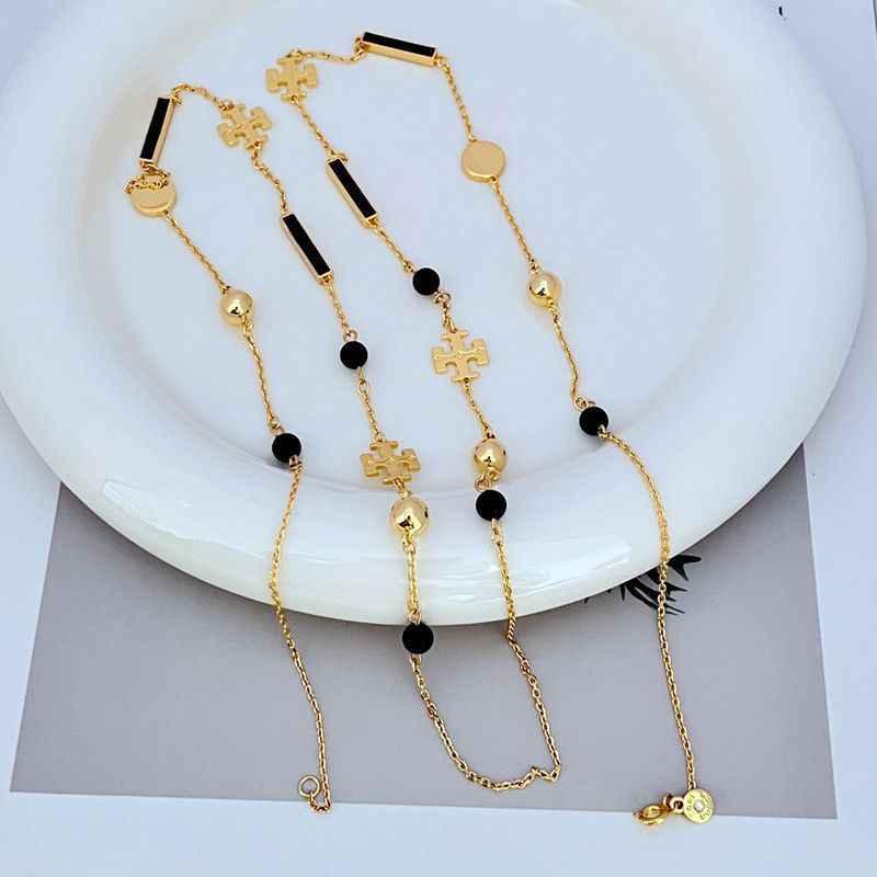 Tory Burch patchwork enamel sweater necklace with gold chains, black enamel bar, cross charm