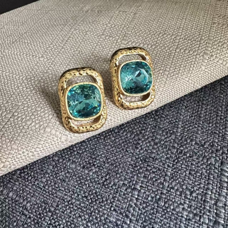 Square crystal stud earrings with teal stones in gold-tone square settings.