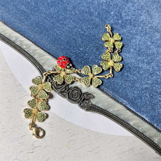 Ladybug and clover charm bracelet with gold-toned chain and green glitter clovers