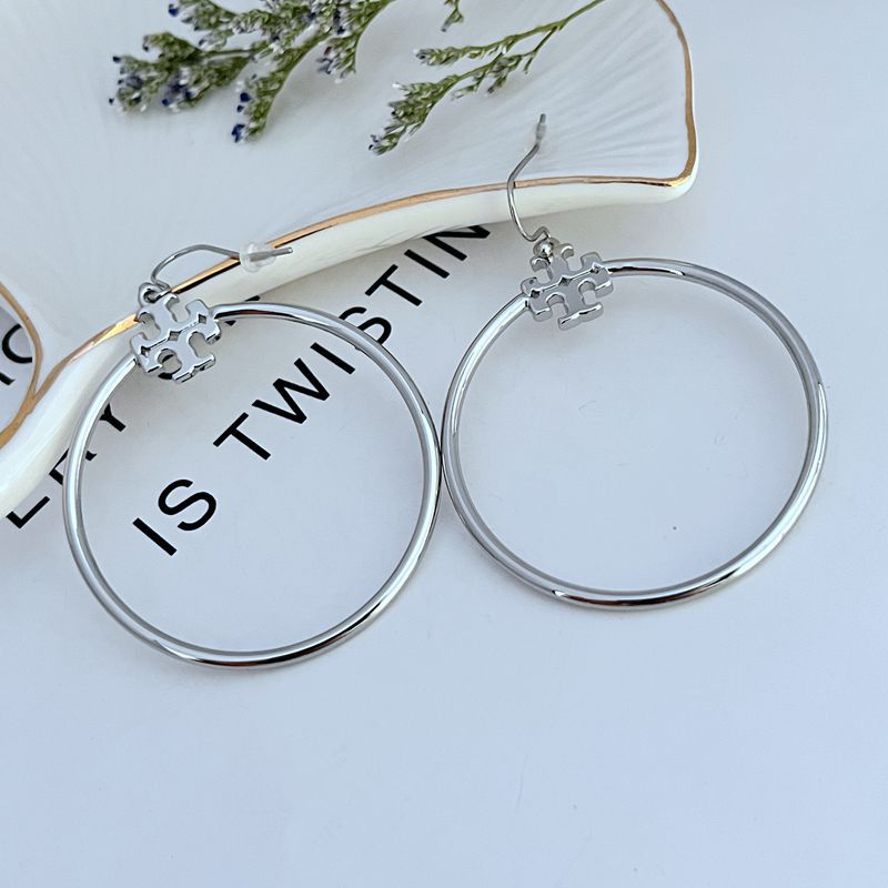 Large round silver hoop earrings with small geometric charm drop