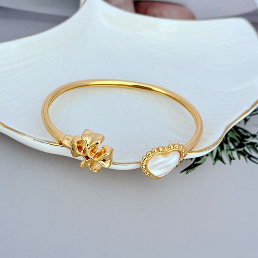 Gold-tone open bracelet showing heart clasp and mother-of-pearl heart charm